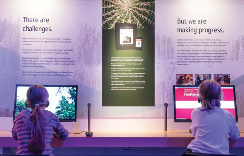 Two children sitting at interactive screens in the Our LIving Languages exhibit