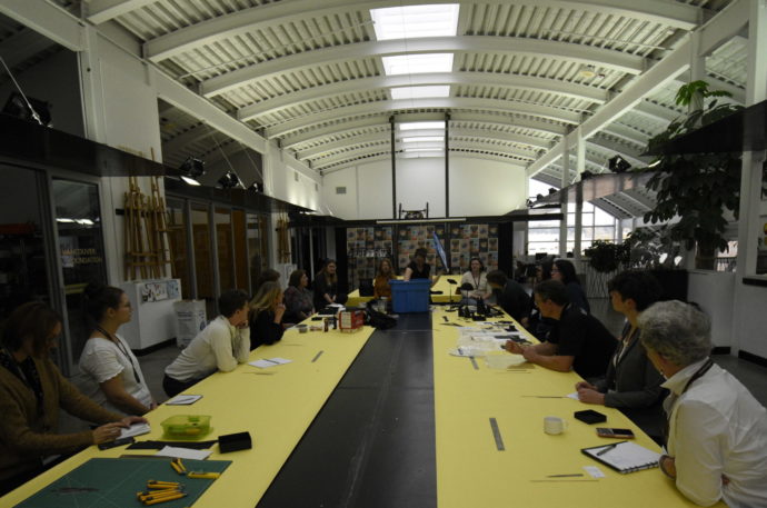 Group of people sitting at a large yellow table with tools